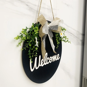 Side view of a round wooden Welcome sign with faux greenery and a layered burlap bow