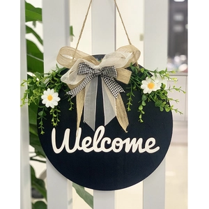 Rustic round wooden welcome sign with white daisy floral decor and burlap bow for door