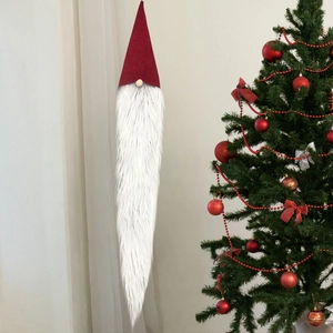 Detail of red plush Christmas gnome ornament with long white beard on a decorated tree
