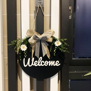 Detail of wooden welcome wreath with artificial leaves, daisies and a plaid burlap bow