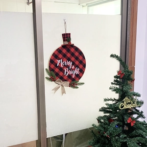Detail of red and black plaid Christmas wreath with Merry & Bright text and pine needles
