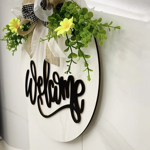 Rustic round wooden welcome sign with artificial greenery and black and white buffalo plaid bow