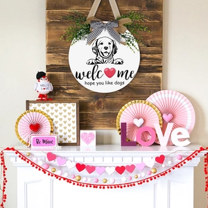 Round wooden welcome sign with a dog pattern, plaid bow and faux greenery for home decor