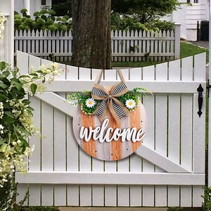 Rustic wooden welcome sign with orange stripes, black white bow, and green ivy decor