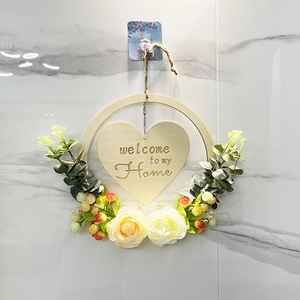 Detail of wooden welcome sign wreath with cream roses and eucalyptus leaves for front door