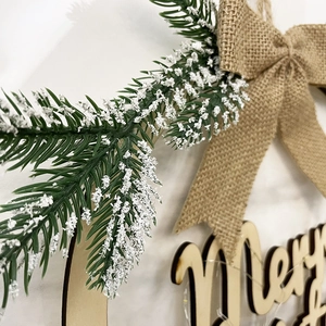 Rustic wooden Merry Christmas door wreath with snow-tipped pine needles and burlap bow