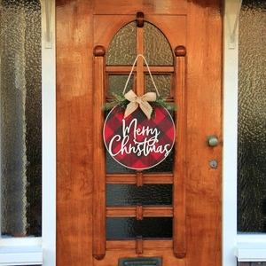 Detail of red and black buffalo plaid Christmas wreath with pine needles on a door