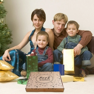 Brown kraft gift box with Best Wishes logo shown against a warm family holiday background