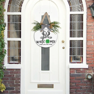 Close-up of a wooden welcome door sign with dog pattern and green clover detail