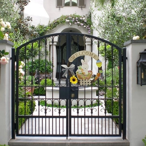 Easter wreath welcome sign featuring rabbits and sunflowers on a black iron gate