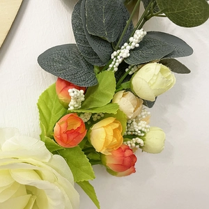 Detailed close-up of cream roses and green leaves on a handcrafted wooden welcome sign