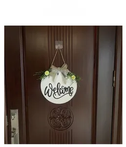 Detail of wooden welcome sign with yellow daisies and burlap bow on a dark door