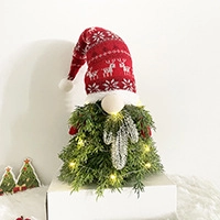 Detail of glowing Christmas gnome ornament with red reindeer hat and warm LED lights