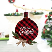 Detail of round buffalo plaid Christmas ornament with top hat, pine needles and red berries