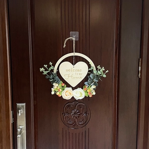 Detail of wooden welcome sign with heart plaque and roses on front door decor