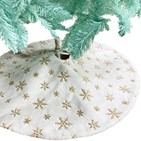 Detail of white Christmas tree skirt with golden snowflake patterns and velvet texture