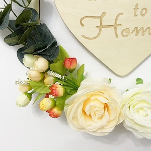 Detail of wooden heart plaque with Home engraving, silk roses and eucalyptus leaves