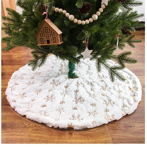 White plush Christmas tree skirt with gold sequin snowflakes on wooden floor