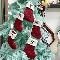 Close-up of five mini red knitted Christmas stockings with white faux fur and letter embroidery