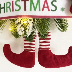 Detail of red felt Christmas elf legs with red and white striped socks and festive banner