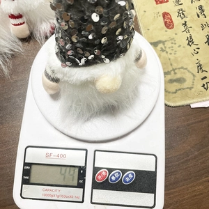 Detailaufnahme einer Weihnachtswichtel-Puppe mit Pailletten, Gewicht 49g auf Waage