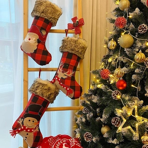 Three red buffalo plaid Christmas stockings with Santa, reindeer and snowman hanging on a wooden ladder