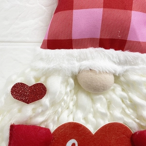 Macro detail of gnome plush decoration featuring red heart sequin and plaid hat texture