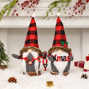 Pair of Christmas gnomes with red-black plaid hats and JOY sign on a snowy background