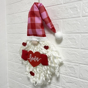 Valentine gnome ornament with love heart and red plaid hat hanging on a white wall