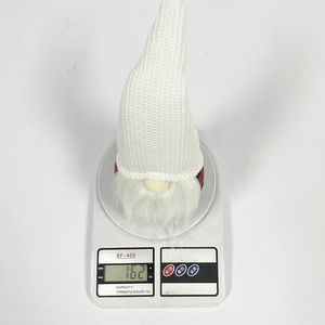 Détail d'un gnome de Noël tricoté blanc pesé à 162g sur une balance électronique