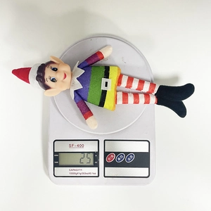 Close-up showing a colorful rainbow Christmas elf plush doll on a white scale weighing 25g