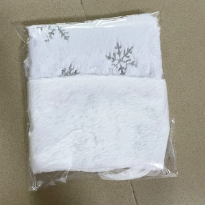 Detail of white plush Christmas stocking with silver sequin snowflake embroidery in packaging