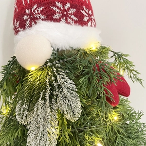 Close-up of LED glowing Christmas gnome with red knitted snowflake hat and green needles
