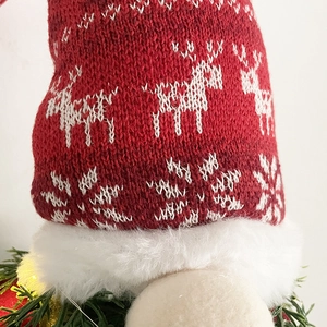 Close-up of a handmade red knitted gnome hat featuring reindeer and snowflake patterns