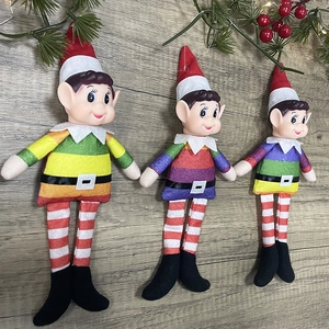 Set of three colorful rainbow Christmas elf ornaments with red hats on wooden background