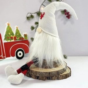 Close-up of a faceless Christmas gnome with a white elk hat on a natural wood base