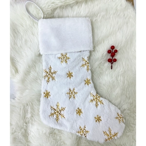 White plush Christmas stocking with gold sequin snowflakes on soft furry background