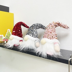 Nahaufnahme von drei Weihnachtswichteln mit Paillettenhüten und weißen Bärten auf Holz