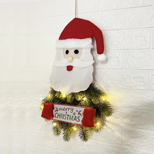 LED lighted Santa Claus Christmas wreath with merry Christmas sign hanging on white brick wall