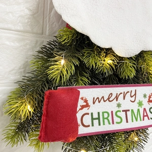 Detail of Christmas wreath featuring pine needles, warm LED lights, and Merry Christmas sign