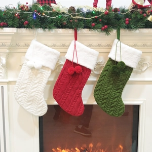 Detailed cable knit Christmas stockings with faux fur trim and pom-poms on a fireplace
