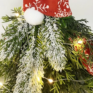 Close-up of a Christmas gnome tree with red snowflake hat and warm LED string lights