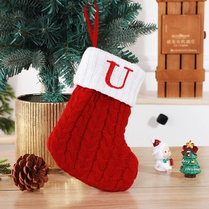 Dettaglio calza di Natale in maglia a trecce rossa con bordo bianco e lettera U