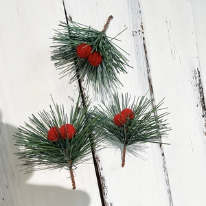 Set of three artificial Christmas pine needles with red berries on white wood background