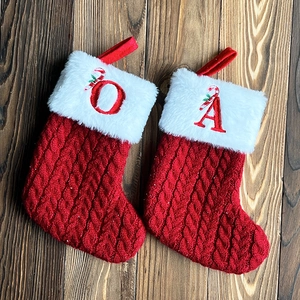 Detail of red cable knit Christmas stocking with white faux fur cuff and letter embroidery