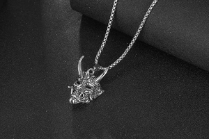 Détail macro du pendentif masque Hannya en acier titane argenté avec sculpture fine