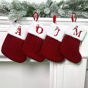 Detail of red cable-knit Christmas stockings with white faux fur and embroidered letters