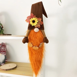 Close-up of autumn harvest gnome with sunflower hat and pumpkin charm on wooden shelf