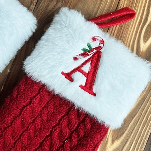 Close-up of red knitted Christmas stocking with white fur trim and embroidered letter A