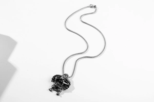 Macro shot of antique silver gargoyle pendant with intricate wing texture on bead chain